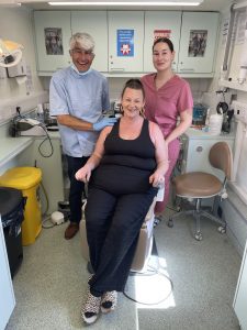 Person in dentist's chair with dentist and dental hygienist